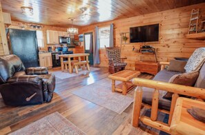 A cozy cabin interior with a living room, dining area, and kitchen.