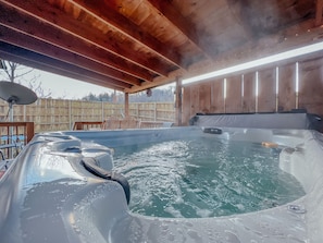 Un jacuzzi con cubierta de madera y sillas, rodeado por un cerco de madera.