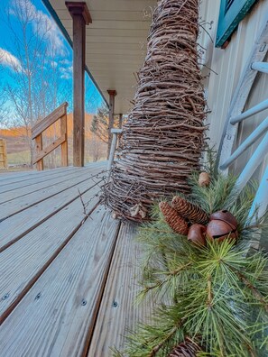 Une terrasse en bois agrémentée d’une composition décorative comprenant des pommes de pin et des branches de pin.