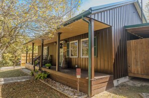 Une cabane en bois avec un porche, un espace extérieur couvert aménagé en salon et une cour clôturée.