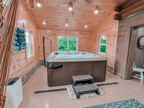 A wooden cabin with a hot tub, two steps, and a dartboard.