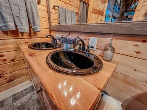 A wooden bathroom with two sinks, a towel rack, and a mirror.