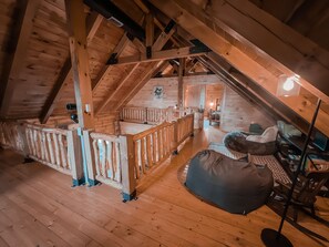 A wooden interior with a loft bedroom, a staircase, and a bean bag chair. - Ash Ridge Lodge in Hocking Hills (Laurelville)