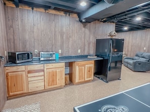 A kitchen with wooden cabinets, a microwave, a toaster, and a refrigerator. - Ash Ridge Lodge in Hocking Hills (Laurelville)
