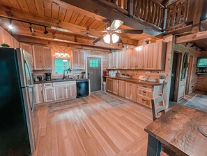 A spacious kitchen with wooden cabinets, a stainless steel refrigerator, and a ceiling fan. - Ash Ridge Lodge in Hocking Hills (Laurelville)