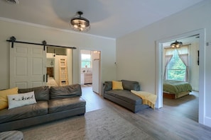 A modern living room with a sofa, a coffee table, and a bed in the adjacent room.