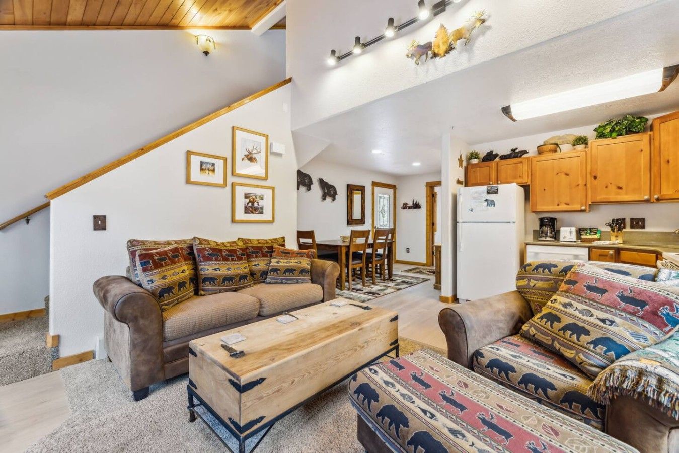 Una sala acogedora con un sofá, un reposapiés y una zona de comedor con sillas y una mesa.
