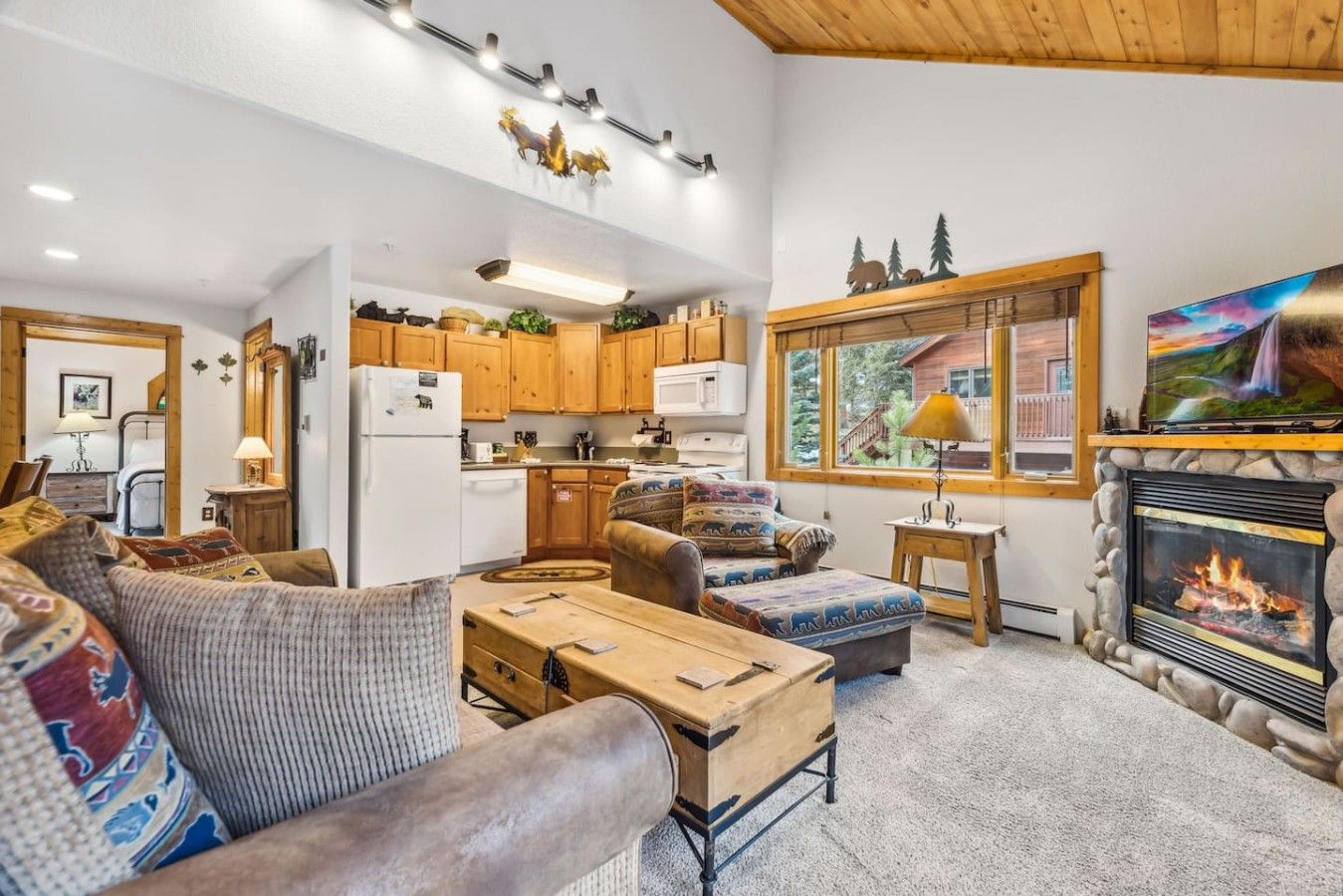 Una sala de estar acogedora con chimenea, televisor y una zona de cocina con armarios de madera.