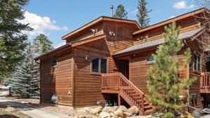 A wooden cabin with a staircase leading to the entrance, surrounded by trees and rocks. - Fall River Hideaway • Peaceful • Near RMNP (Estes Park)