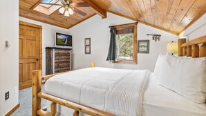 A bedroom with a wooden bed frame, a ceiling fan, a TV, and a window with curtains. - Fall River Hideaway • Peaceful • Near RMNP (Estes Park)