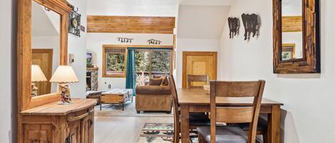 A dining area with a wooden table and chairs, a mirror, and a rug with animal prints.
