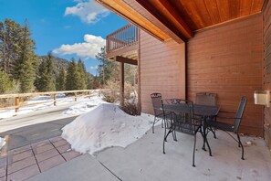 A wooden building with a balcony, outdoor seating, and a snow-covered ground.