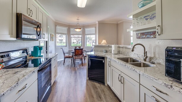 A modern kitchen with a dishwasher, double sink, and a dining area with a table and chairs.