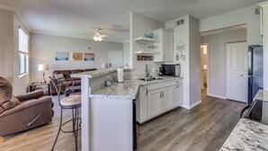 A modern kitchen with white cabinets, a marble countertop, and a built-in oven.