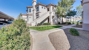 A residential building with a central staircase, a covered driveway, and a well-maintained lawn.