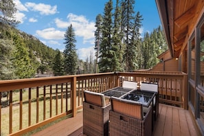 A wooden deck with a table and chairs, overlooking a forested area. - Scenic Riverfront Escape • RMNP • River Views (Estes Park)