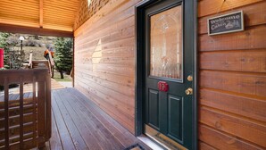 Entrada a una cabaña de madera con un letrero de bienvenida, puerta número 19 y un porche cubierto.