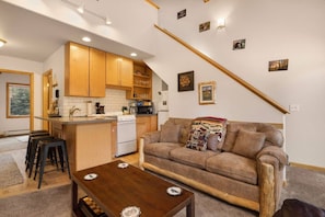 A compact living space with a kitchen, a sofa, and a coffee table. - Scenic Riverfront Escape • RMNP • River Views (Estes Park)