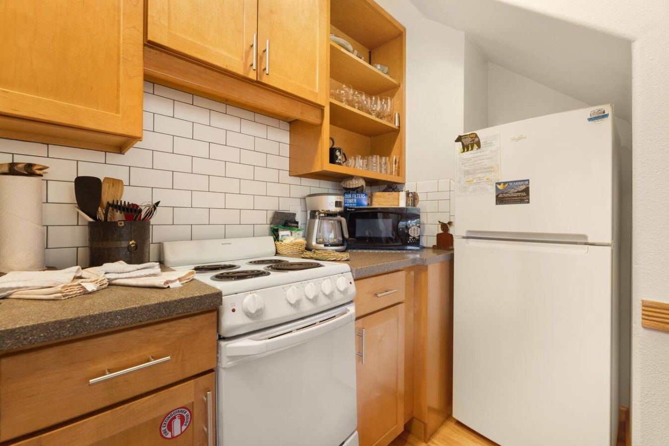 Una cocina con armarios de madera, una estufa blanca, un microondas y un refrigerador blanco.