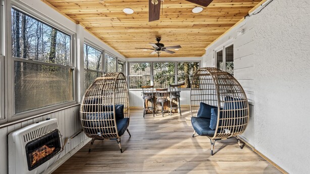 Un solárium con techo de madera, ventanas amplias y dos sillones colgantes.