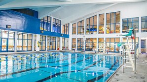 Una piscina interior con carriles delimitados, un trampolín y una silla para socorristas.
