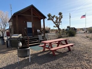 Eine Holzhütte mit Veranda, Grill und Picknicktisch.