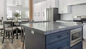Una cocina moderna con armarios blancos, encimera de granito y electrodomésticos de acero inoxidable.