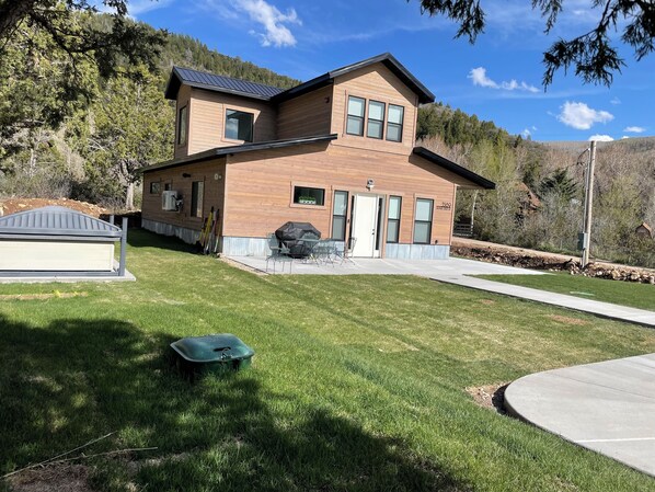 A two-story house with a covered patio, a barbecue grill, and a shed.