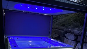 Una bañera de hidromasaje con cerramiento de vidrio e iluminación azul.