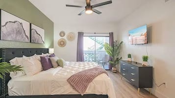 Une chambre avec un lit, un ventilateur de plafond, une télévision et un balcon avec vue.
