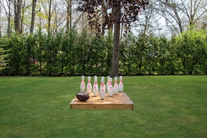 A lawn bowling setup with pins and a ball on a wooden platform.