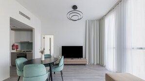 A modern living room with a dining area, a flat-screen TV, and a sofa.