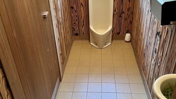 A small, narrow bathroom with a wooden vanity, a urinal, and a toilet.