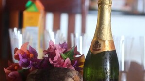 Ein Tisch mit einer Champagnerflasche, einer Blumenschale und einem Teller Essen.