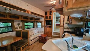 L'intérieur d'un véhicule récréatif comprend un coin repas, une petite cuisine et un espace salon offrant une vue sur l'extérieur.