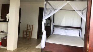 Una cama individual con dosel en una habitación con suelo de baldosas y una silla de madera.