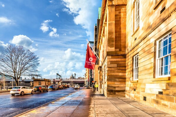 A hotel with a red flag, a wet street, and a clear sky.
