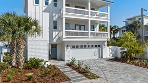A multi-story residential building with a garage, white exterior, and balconies. - The Twin Palms at Vilano Beach,  Private Pool - Steps From Beach - Minutes from everything (Vilano Beach)