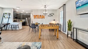 Eine moderne Küche mit dunklen Schränken, einem Edelstahlkühlschrank und einem Essbereich mit Holztisch und Stühlen.