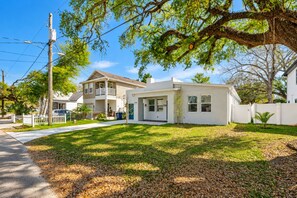 A two-story house with a front yard, a driveway, and a white fence.