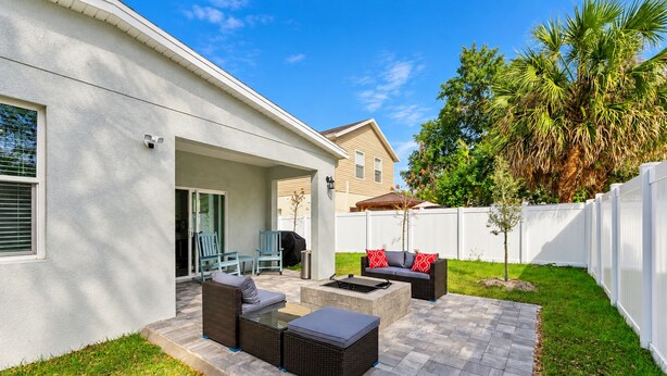 Un patio con mobiliario exterior, una parrilla y una valla blanca.