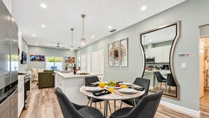 Una cocina moderna con comedor, que incluye una isla central, sillas negras y un espejo grande.