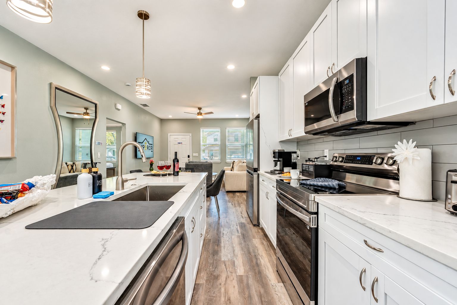 A modern kitchen with white cabinetry, stainless steel appliances, and a marble countertop.