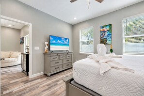 A bedroom with a bed, a dresser, a television, and artwork on the walls.