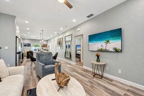 Een moderne woonkamer met een open haard, een eethoek en een keuken op de achtergrond.