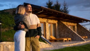 A couple embracing in front of a rustic building with a stone exterior and a wooden deck. - Zemunice Kneževic  (Banja Luka)