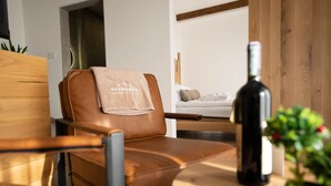 A modern room with a leather chair, a bottle of wine, and a small plant on a wooden table. - Zemunice Kneževic  (Banja Luka)