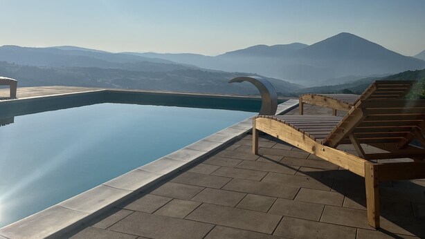An infinity pool with a clear view of mountains and a wooden deck with lounge chairs. - Zemunice Kneževic  (Banja Luka)