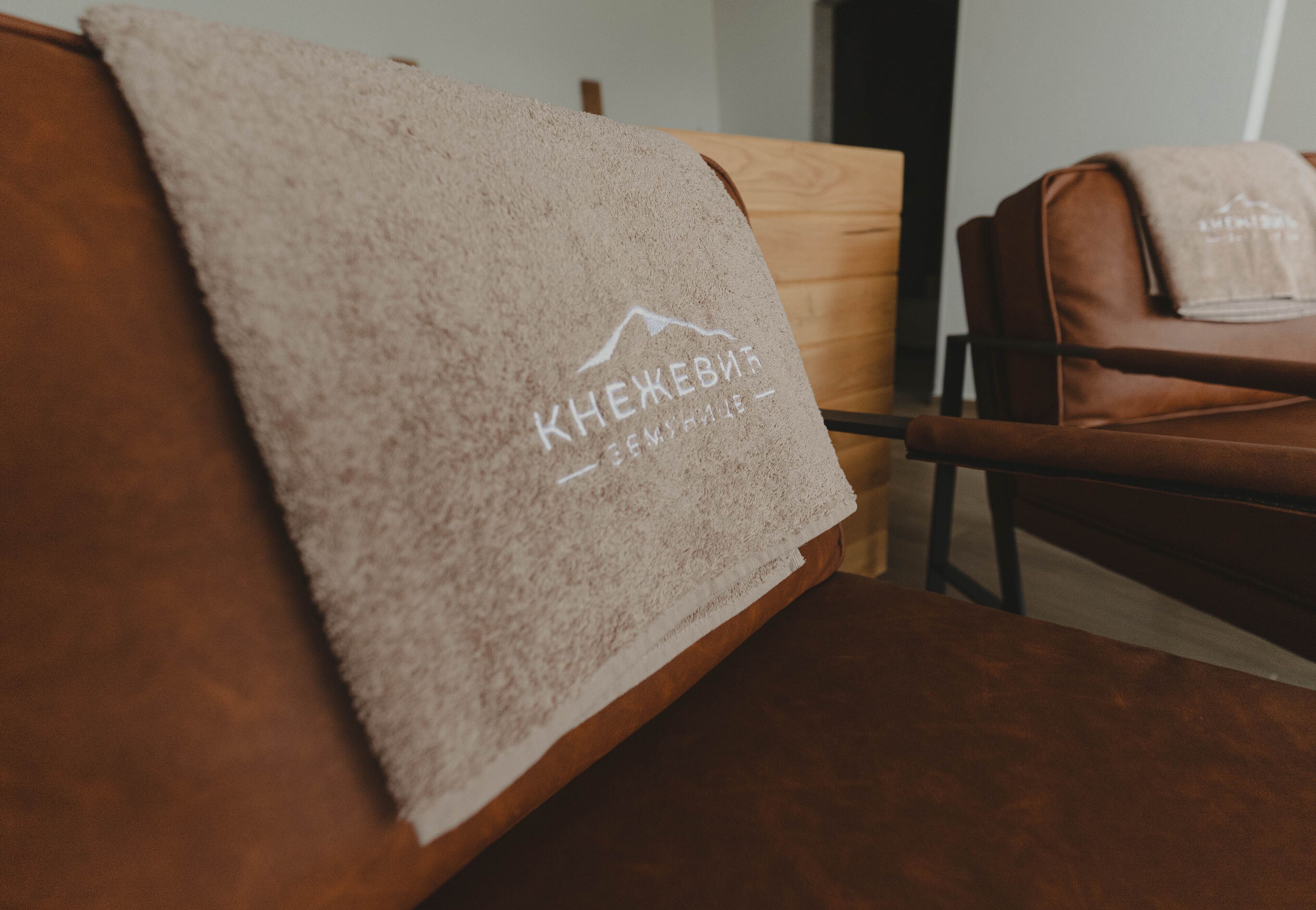 A wooden chair with a towel draped over it, featuring a mountain logo and text.