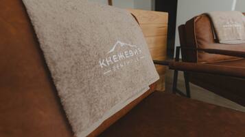 A wooden chair with a towel draped over it, featuring a mountain logo and text.